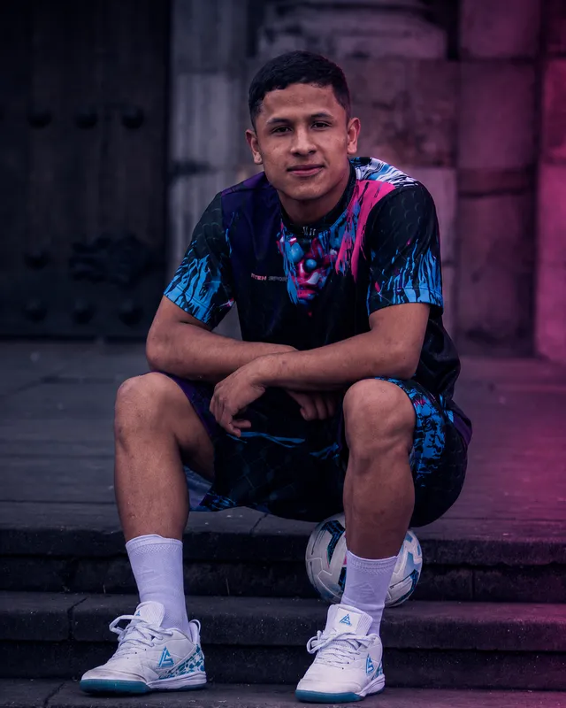 Jugador sentado en las escalas con balón y las Bogotá Blanca puestas
